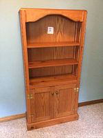 Front view of the wood bookshelf showing two open shelves and a two-door cabinet below.