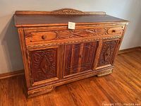 Full view of the wood buffet showing carved designs and drawer above two cabinet doors.