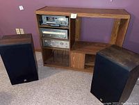 Full view of wooden entertainment unit containing cassette player, tuner, and amplifier, with two speakers on carpeted floor