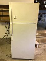 Front view of white General Electric refrigerator with a top freezer and bottom refrigerator door, showing size and condition.