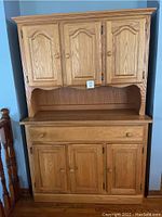 Full frontal image of two piece light wood kitchen hutch showing the upper and lower cupboards and drawer.