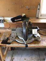 Front view of the miter saw showing saw blade, base, and handle on a wooden workbench.