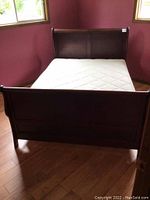 Queen bed with wooden headboard and footboard, dark finish, showing full bed setup from foot end.