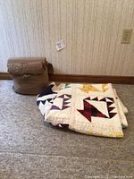 Rolled brown sheet set with pillowcases and folded quilt on carpeted floor near wall