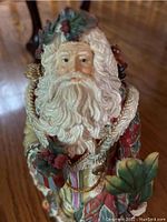 Close up photo of Fits and Floyd musical Santa figurine showing facial and upper body details with white beard, red suit, and holly accents.