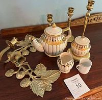 White and gold Sadler tea set along with three gold candle holders and two gold wall candle holders displayed on wooden surface.