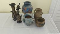 Photo showing all four ceramic pottery pieces placed on a white surface against a plain wall.