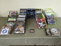 Wide angle photo showing all items spread on table including boxed games and PC discs, and X-Men figurine in original packaging.