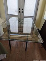 Full view of rectangular glass dining table top showing clear beveled glass reflecting double door behind