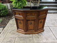 Front view of solid wood hall table with smoked glass top and three front panels with handles.