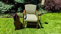 Photo showing inclusion of gingham occasional chair, wooden magazine rack, and metal candle holder together on grass outdoors