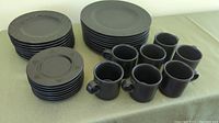 Full set of Pfaltzgraff Midnight Sun dinnerware featuring plates and mugs arranged on a green tablecloth.