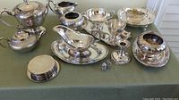 Entire set arranged on table showing coffee pot, tea pot, cream and sugar, coasters, salt and pepper shakers, candlestick, trays and bowls