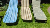 Three lounge chairs with different fabric patterns set on grass outdoors, showing front and upper view.
