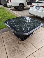 Photo showing octagonal black marble-look coffee table from an angle, emphasizing shape and finish.