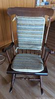 Front view of vintage solid wood rocking chair with striped seat and back cushions