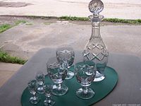 Photo of full set including the Waterford Kerry decanter with stopper, three water goblets, and three cordial glasses on a table outdoors.