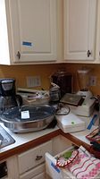Overview photo showing multiple small kitchen appliances on a counter including a coffee maker, rotisserie, blender, fryer and others.