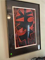 Framed black and red abstract print hung on wall.