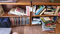 Pair of wooden bookcases filled with various books and items showing condition and size.