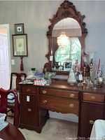 Full view of wooden buffet with attached decorative mirror, showing brass hardware and scalloped trim, with various items on top (not included).