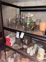 Metal candleholders and various glass bottles and jars on black shelving