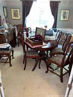 Wide view of dining table surrounded by seven cherry wood dining chairs with animal print upholstered seats. Four chairs have cabriole legs, and three chairs have straight legs.