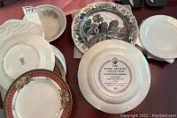 Top view of multiple plates including Spode Archive Collection Tradition series with black and white scenic designs, Noritake luncheon plates, silver rimmed dessert plates clustered together