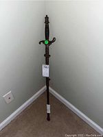 Full view of large military sword and attached scabbard leaning against a wall, showing the full length and overall condition.