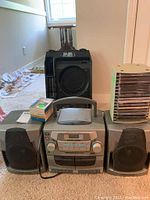 Photo of Philips Magnavox AZ2750CD radio cassette recorder with two detachable speakers, stacked CDs, and a small box of slides or media.