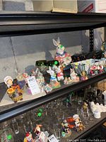 Shelf showing ceramic animal figurines including rabbits and other animals, along with glassware pieces below