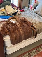 Fur stole laid flat on bed, showing entire stole with soft, glossy brown fur.