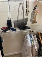 Image of closet shelf showing silver glitter handbag, two other handbags, black pouch, black and blue gloves, and coiled red bowtie on wire shelf