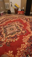 View showing large red medallion pattern on area rug with floral motifs on floor.