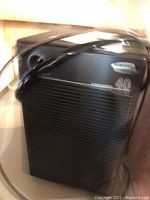 Black Samsung dehumidifier with power cord draped over, placed indoors on wooden floor.