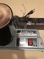 Close up of the Delta brand nameplate and control panel showing 4" belt and 6" disc capacity, model 31-400C, red on/off switch, and power cord.