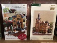 Photo of two boxed Department 56 holiday village buildings: City Park Carriage House and St. Marys Church.