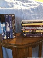 Two photos showing a selection of DVDs on a wooden round table against a cloth background. Left side shows BBC nature documentary boxed sets including The Blue Planet and The Life of Mammals. Right side shows assorted DVDs including music and film titles such as Bee Gees One Night Only and Open Range.