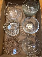 Top view of six assorted clear glass bowls arranged in cardboard box.