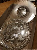 Two clear glass cake plates: one with starburst pattern and scalloped edge, one plain shallow bowl plate
