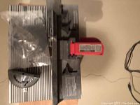 Top-down view of router table insert plate and attached fence with red adjustment lever and components still in packaging.