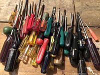 Photo of assorted screwdrivers laid out on a surface, showing various handle colors and shaft lengths