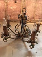 Chandelier light fixture viewed from above showing metal arms, floral petal bulb holders and faux candle sleeves.