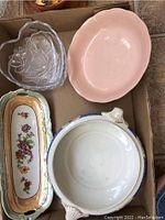 Top view of six vintage serving dishes including Peach Petal pink dish, white Grindley round dish, rectangular floral Booths dish with chip, and two heart-shaped glass dishes.