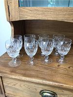 Eight Waterford Crystal Colleen short stem water glasses arranged on a wooden surface, front and side views visible.