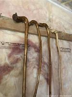 Four wooden walking sticks hanging on a wooden rack, showing their overall shape and hand grips from a side angle.