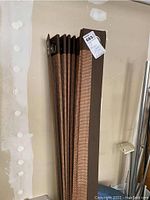 Curtains stacked against a wall, showing length and top edge with grommets.