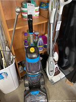 Front view of Bissell ProHeat carpet cleaner unit with blue and black color and accessories behind.
