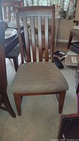 Front view of a solid wood dining chair with fabric seat and vertical slat back
