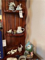 Overall display of all dolphin and seal collectibles on wood shelving and beside shelf space displaying the clock and other small items.